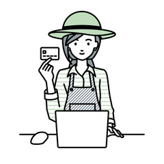 デスクで座ってPCを使いながらクレジットカードを手に持っている農家の女性