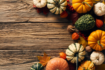 Harvest or Thanksgiving background with pumpkins, fall leaves and flowers on wooden table. Flat lay composition, top view, copy space