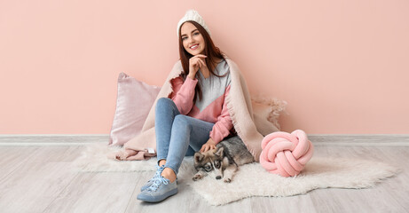 Young woman with funny husky puppy sitting near pink wall © Pixel-Shot