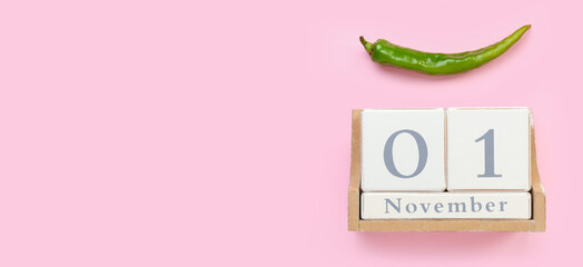 Calendar with date NOVEMBER 1 and hot chili pepper on pink background with space for text. World...