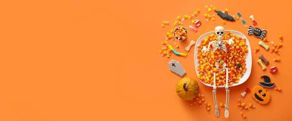 Different Halloween sweets on orange background with space for text, top view