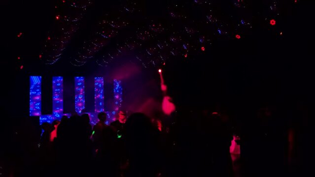 Group of Unrecognizable Young People Dancing during a Party on Dance Floor With Spinning Disco Balls and Lots of Lights hanging from the Ceiling. 4K Resolution.