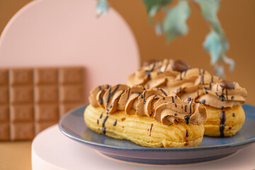 Eclairs chocolate cakes.Custard cakes with chocolate cream and chocolate bar on brown background.Sweets and desserts. Baked goods and desserts.