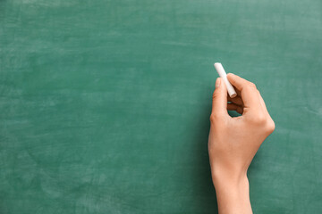 Naklejka premium Female hand with chalk against green blackboard
