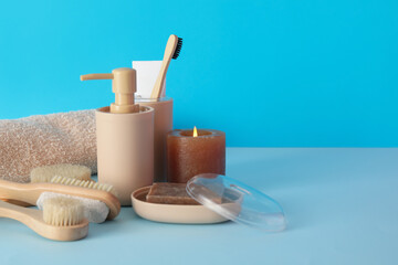 Bath accessories with burning candle on blue background
