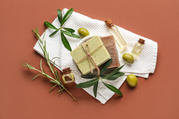 Composition with soap bars and bottles of essential olive oil on color background