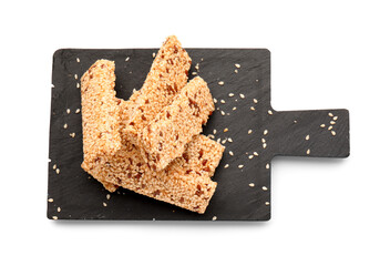 Slate board with tasty sesame kozinaki on white background