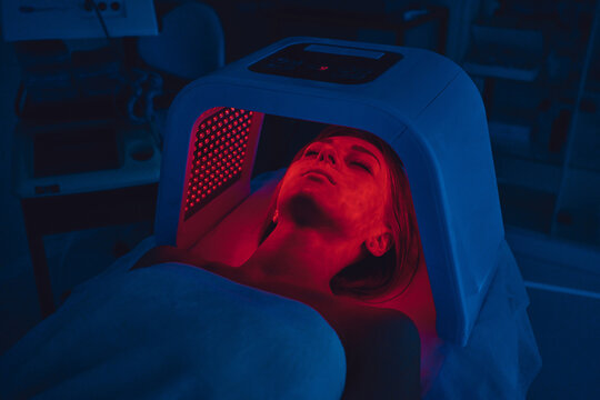 LED Red Light Is Treating The Facial Skin Of A Young Woman.