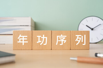 年功序列と書かれたブロックが置かれたデスク
