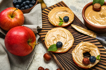 Wooden board of tasty apple rounds with nut butter on light background, closeup