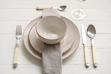 Simple dinnerware with plates and cutlery on white wooden table