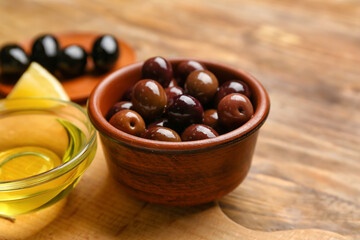 Bowl of delicious olives on wooden background, closeup