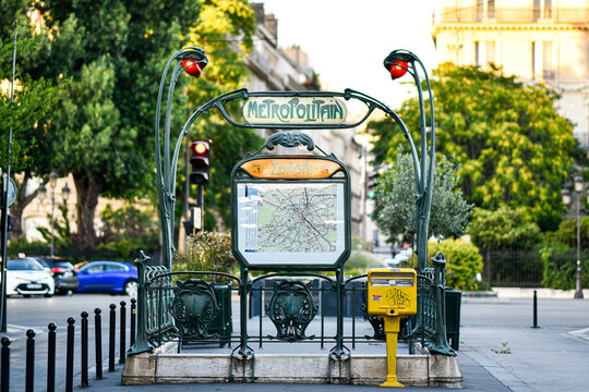 Sign with the subway logo (yellow symbol) in front of a parisian metro (metropolitain) station (Europe, line 3) during a summer day in Paris, France.