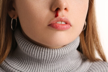Young woman with nosebleed on white background, closeup