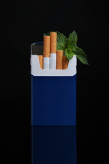 Pack of menthol cigarettes and mint on black background