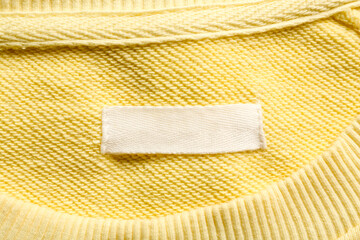 Blank clothing label on yellow sweater, top view