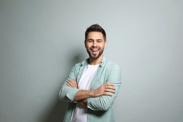 Young man laughing on light grey background. Funny joke