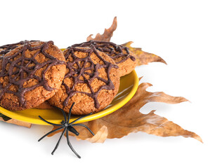 Plate with Halloween spiderweb cookies and fallen leaves on white background