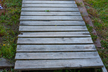 The path of unpainted boards lies on the green grass