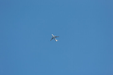 Fototapeta premium Flying passenger plane high against the blue sky