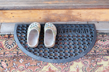 Colored slippers lie on the wooden porch of the house
