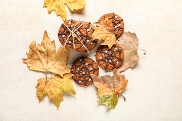 Halloween spiderweb cookies and fallen leaves on white background