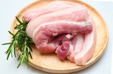 pork on wooden plate with rosemary, fresh raw streaky pork meat for cooking food