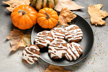 Plate with Halloween mummy cookies, pumpkins, fallen leaves on black and white background