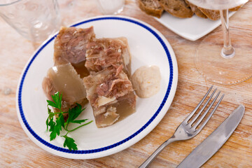 Portion of homemade jelly pork meat with sauce on plate, popular dish of russian cuisine