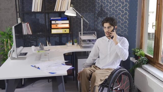Disabled office worker in a wheelchair.
Disabled office worker sitting in a wheelchair and talking on the phone.
