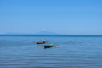 Two traditional wooden fishing canoes in the shallows of blue ocean on a remote tropical island