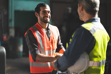 Caucasian factory engineer talking and shaking hands on business cooperation agreement. Successful hand shaking after good deal, workers handshaking each other at heavy industrial production line.