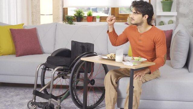 Disabled teenager is crying. Disabled teenager eating at home.
Disabled young man is eating at home and is sad.
