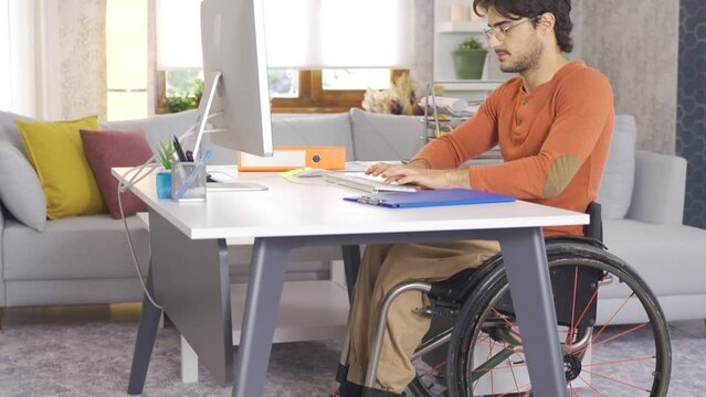 Disabled young man works with computer at home.
Disabled young man freelance takes notes from home and works with computer.
