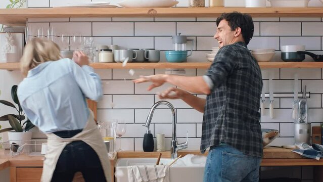 Love, cleaning and kitchen couple play with dish wash foam together in apartment on weekend. Happy, goofy and funny people in romantic relationship commitment enjoy innocent fun in home.