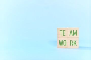 Teamwork and team building business concept. Hand putting together wooden blocks wood puzzle pieces in blue background.