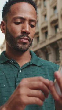 VERTICAL VIDEO: Close up, young man standing on the street using the phone