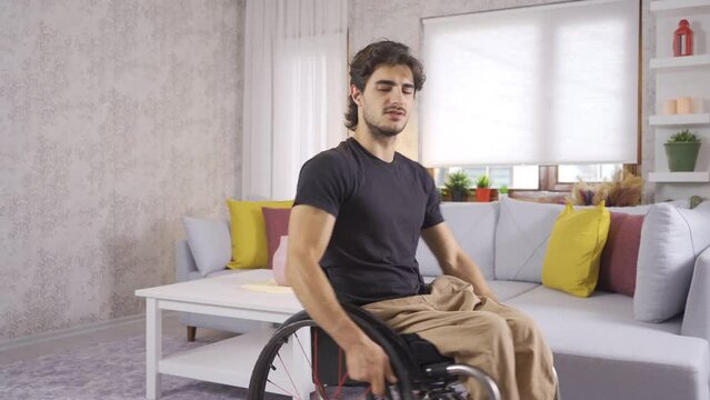Resentful disabled young man sits in a wheelchair.
Frustrated and unhappy, the disabled teenager is alone at home.
