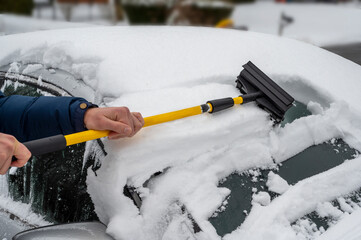 man cleaning snow off his car during winter snowfall. Winter bad weather 