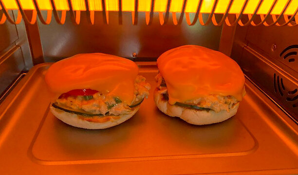 Tuna Melt On A English Muffin Cooking In A Toaster Oven With American Cheese On Top