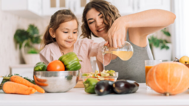 Mom And Daughter Together Prepared A Salad Of Vegetables And Poured With Oil.