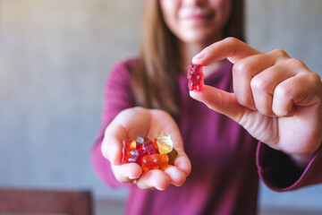 Closeup image of a young woman holding and showing at a red jelly gummy bears