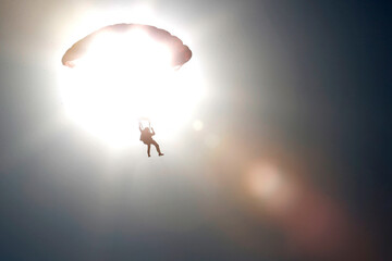 skydiver in the backlit sky.
