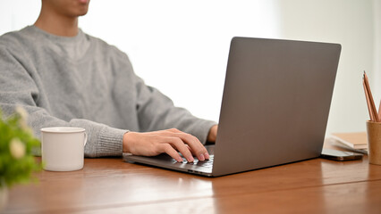 Professional Asian male programmer working at his office desk, using laptop computer