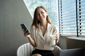 Fototapeta premium Asian businesswoman in formal suit in office happy and cheerful during using smartphone and working.