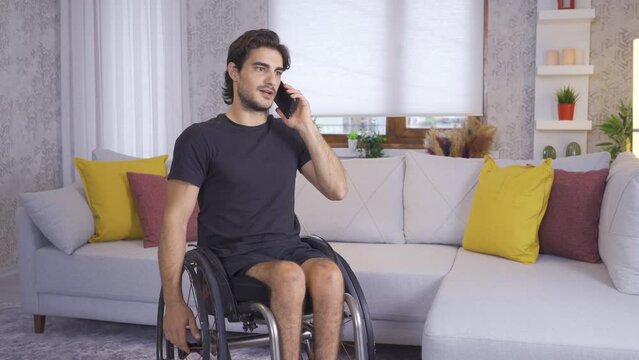 Physically disabled man talking on the phone.
Disabled man sitting in his wheelchair talking on the phone at home.
