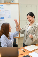 Happy Asian businesswomen celebrate their success, giving high-five