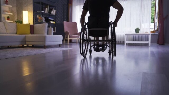 Disabled young man at home in slow motion. 
Disabled young man watching out of the window of the house.
