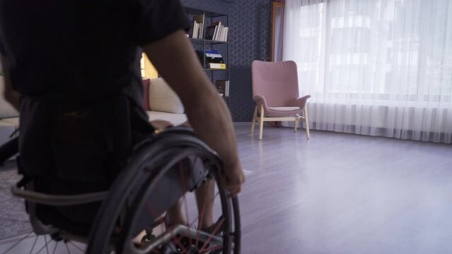 Disabled young man watching out of the window of the house.
Disabled young man at home in slow motion. 
