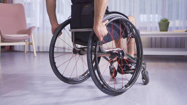 Wheelchair in slow motion.
He is in a wheelchair at home and a disabled teenager is sitting on it.
